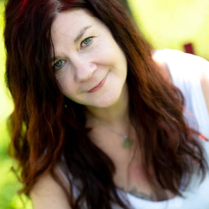 Porträt einer Frau mit langen rotbraunen Haaren im Grünen
