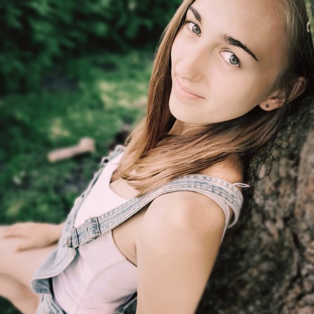 Junge Frau im Grünen, an einen Baum gelehnt