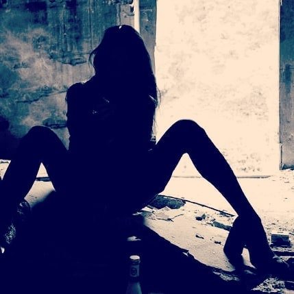 Silhouette einer sitzenden Frau vor hellem Fenster