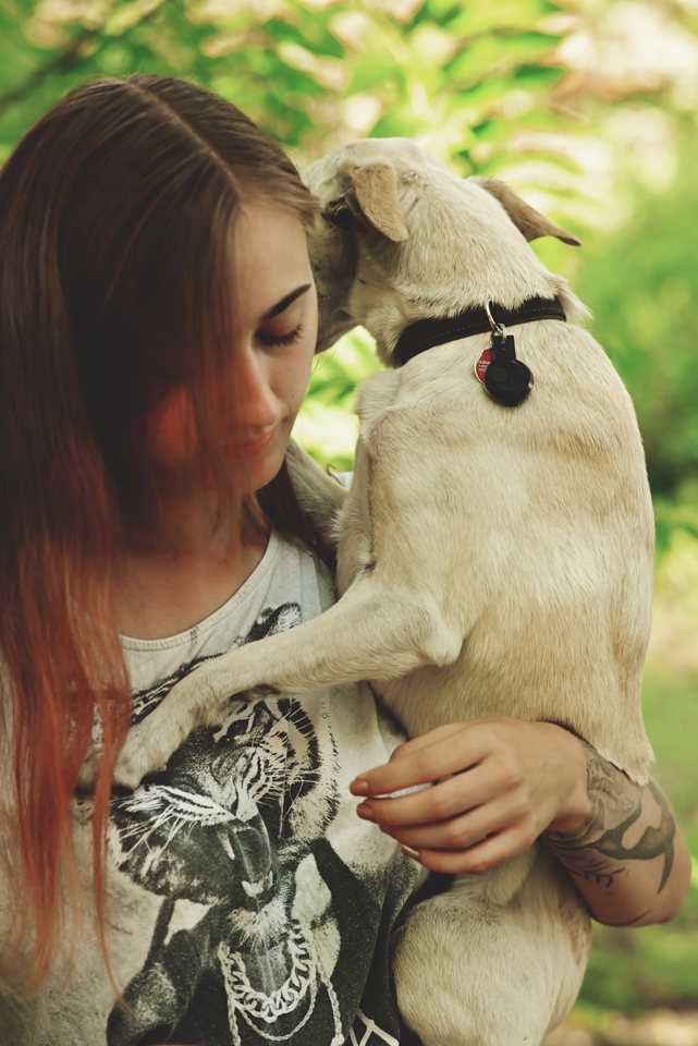 Lou küsst einen hellen Hund, der an ihr hochsteht