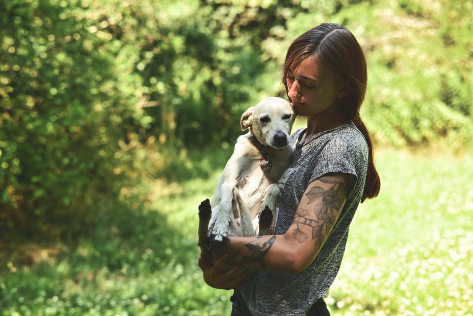 Lou trägt einen kleinen Hund auf dem Arm