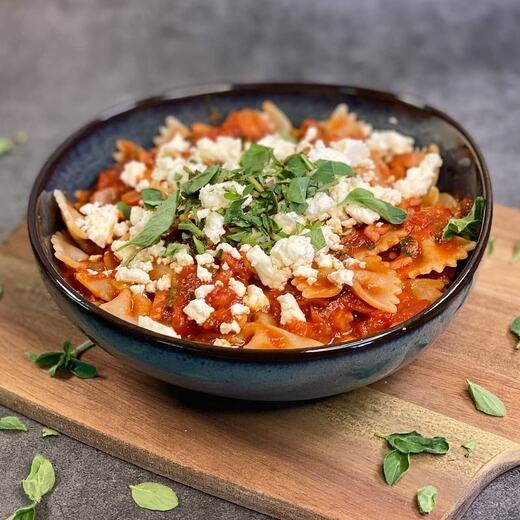 Es gibt Vollkornschleifchen mit Tomatensauce, vielen Gartenkräutern und Schafskäse